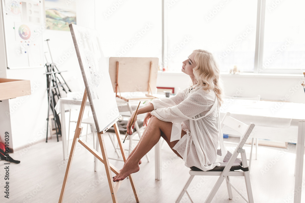 Beautiful woman sitting on chair in a bright room, admiring my painting Beautiful woman sitting on chair in a bright room, admiring my painting