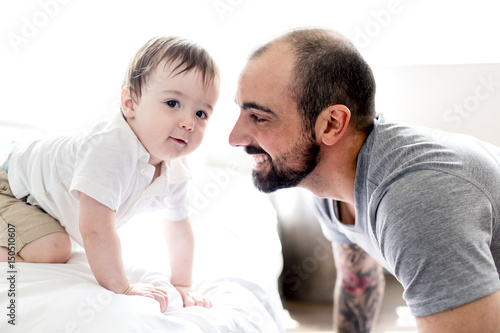 Beautiful man and son lying together on a bed