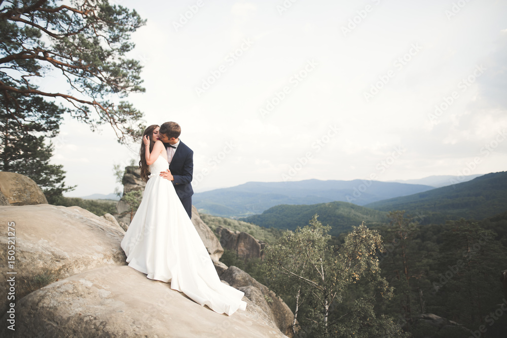 Beautiful happy young wedding couple posing on a background of rock cliff Beautiful happy young wedding couple posing on a background of rock cliff