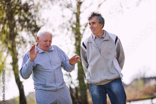 Фототапет Adult son walking with his senior father in the park.