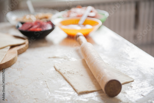 On the table the flour of the hand of the cook roll out the dough, the ingredients.