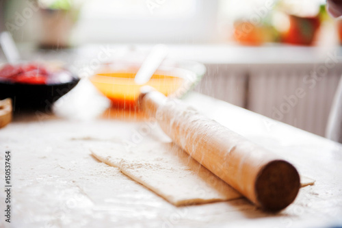 On the table the flour of the hand of the cook roll out the dough, the ingredients.