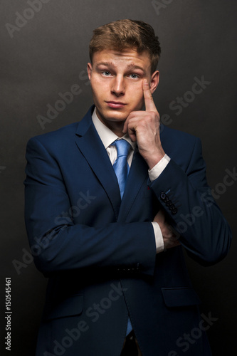 Businessman thinking, over dark background, suit and tie.