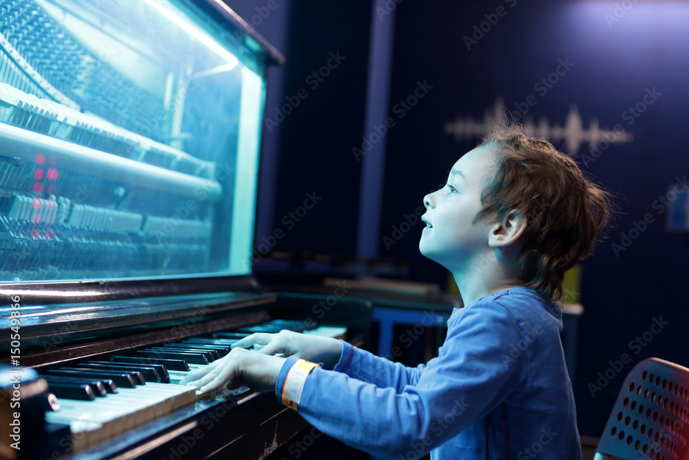 Boy playing on light music piano Boy playing on light music piano