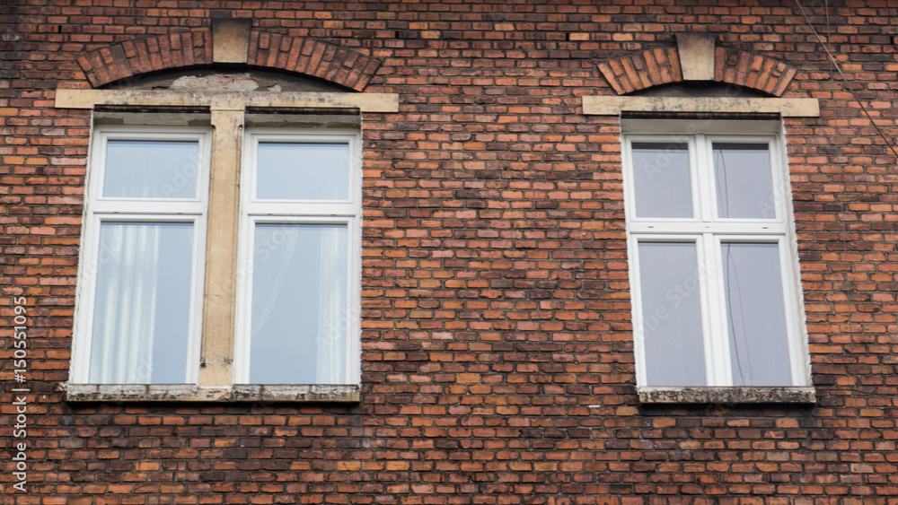Two white wooden Windows on the facade of a brick house Two white wooden Windows on the facade of a brick house