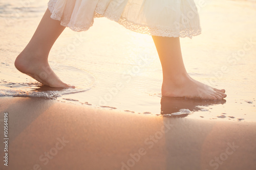 Girl Barefoot are Walking on the Beach in Water. Vacation in Summer at the Sea