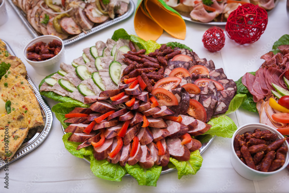 A dish with cheese, salami, sausage and green on the raut table for the celebration