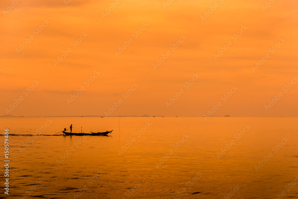 Asian fisherman on wooden boat with sunset time,Beautiful sunrise and silhouette of fishing boat.