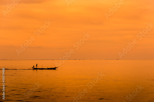 Asian fisherman on wooden boat with sunset time,Beautiful sunrise and silhouette of fishing boat. © Hide_Studio