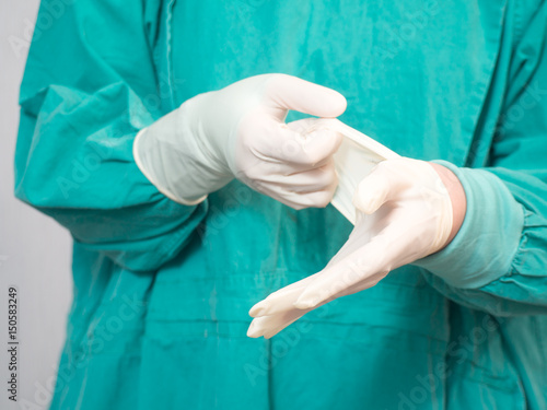 Doctor putting on white sterilized surgical glove