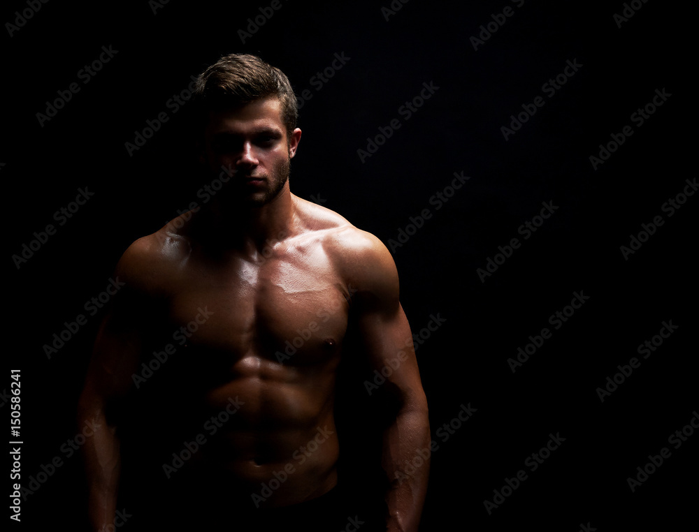 Horizontal studio shot of a young shirtless athletic man with sexy hot muscular ripped body posing on black background copyspace fitness sports athletics muscles gym physique confidence determination.