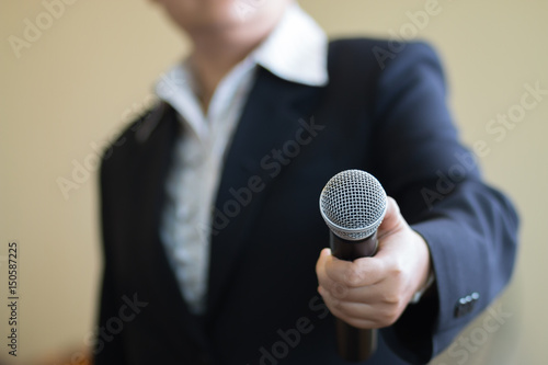 blurred of businesswoman speech and reporter with microphone at presentation in conference