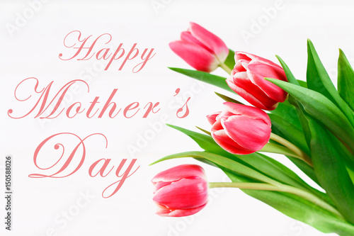 Fototapeta Naklejka Na Ścianę i Meble -  happy mother's day text sign on pink tulips on white rustic wooden background. greeting card concept. sensual tender women image. spring flowers flat lay