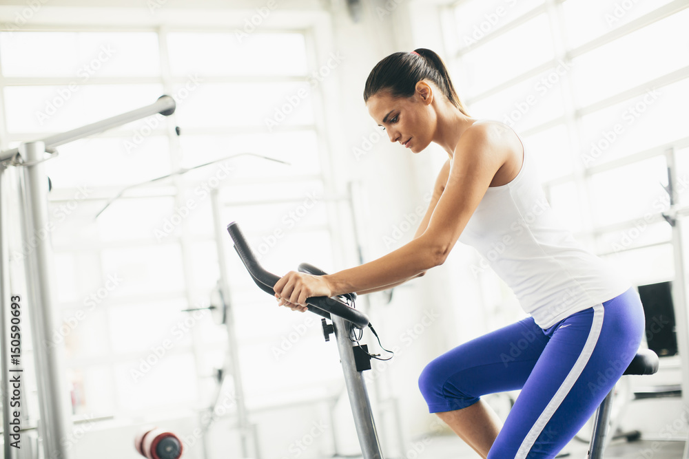 Happy woman riding an exercise bike in gym Happy woman riding an exercise bike in gym