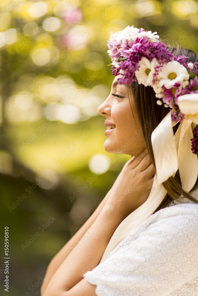 Obraz premium Young woman with flowers in her hair on sunny spring day