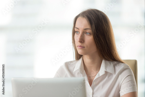 Lost in thoughts businesswoman thinking of solution. Worried female sitting alone in office looking away. Female entrepreneur ponders decision at workplace. Absent minded young woman tired, distracted