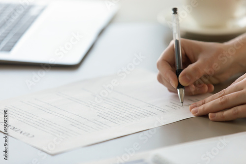 Close up photo of womans hands signs contract. Businesswoman puts signature to partnership agreement concept. Female entrepreneur accepts conditions of deal. Working with business documents in office
