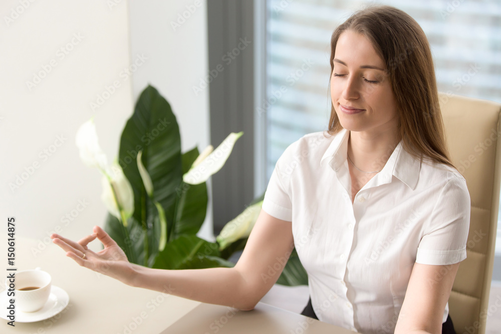 Calm businesswoman meditating in office chair. Female office worker relaxing on workplace. Business lady yoga exercise. Girl resting and relieves work stress with spiritual practices or autosuggestion Calm businesswoman meditating in office chair. Female office worker relaxing on workplace. Business lady yoga exercise. Girl resting and relieves work stress with spiritual practices or autosuggestion