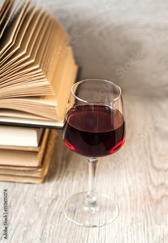 A glass of red wine and books on the table. The concept of rest