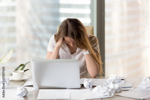Obraz na plátně Desperate businesswoman sitting at the desk with laptop and crumpled paper