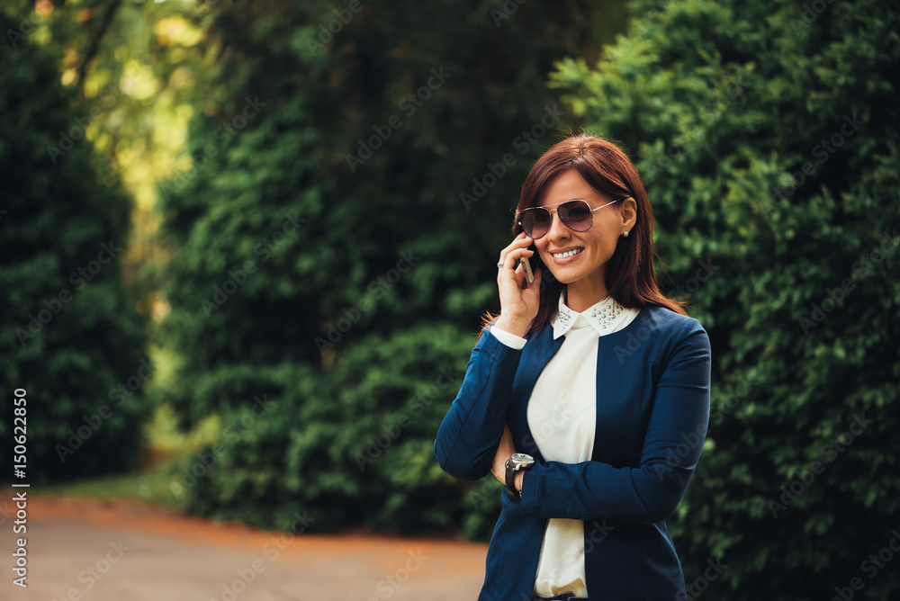 Woman talking on the mobile while exploring the city park