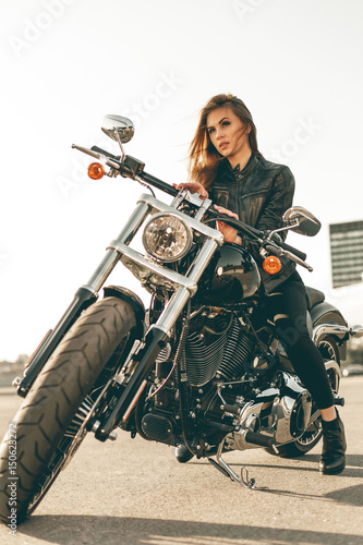 Girl on a motorcycle. She is beautiful, posing on a motorcycle at sunset