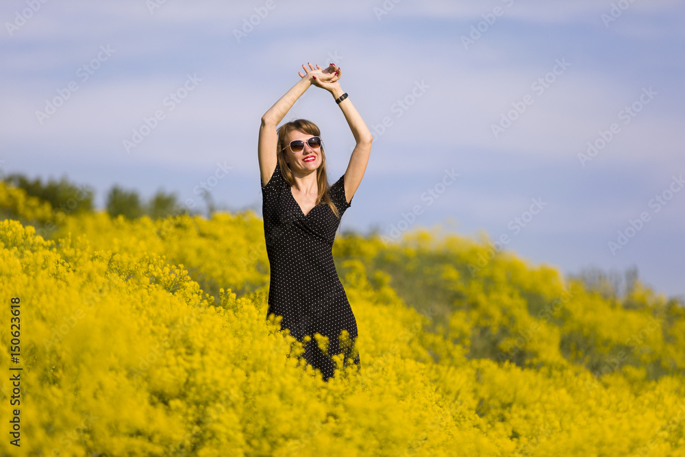 Young woman standing in a field of yellow flowers