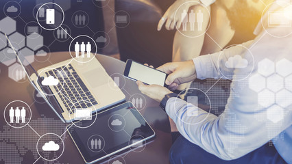 Close-up laptop and digital tablet on table, smartphone in men's hands. Virtual icons with clouds, people, gadgets
