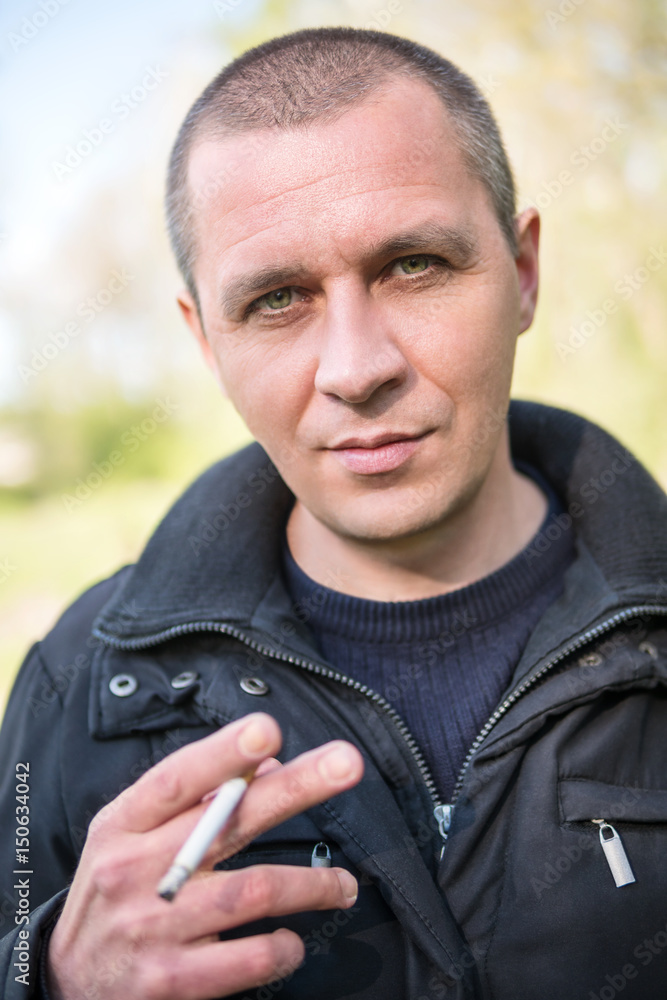 Portrait of a serious man with a lit cigarette in his hands, shot with a shallow depth of sharpness Portrait of a serious man with a lit cigarette in his hands, shot with a shallow depth of sharpness