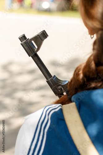 A girl in military uniform holds a Kalashnikov assault rifle