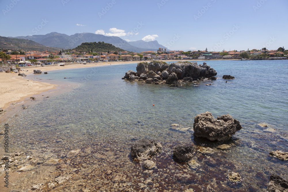 beautiful beach of Stoupa in greece on sunny day in spring on peloponnese with flowers and sunbeds