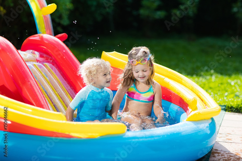 Kids in garden swimming pool with slide