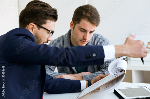 Business young man explaining terms of contract to his client in the office.