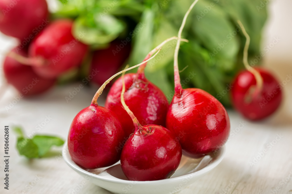 Red radishes in bowl on wooden table. Vegetable of cabbage family. Red radishes in bowl on wooden table. Vegetable of cabbage family.