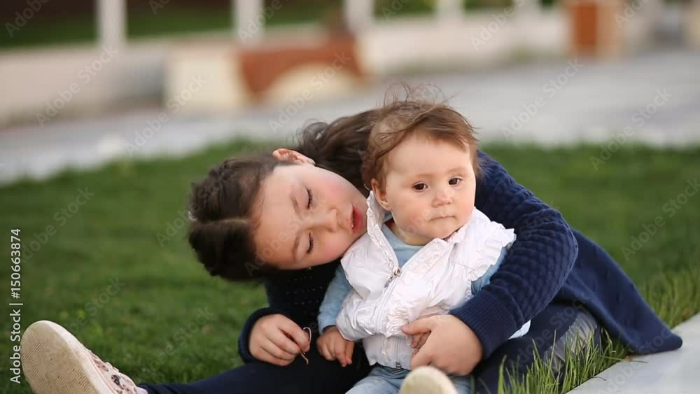 Little pretty baby-girl sitting on green grass in the park at the sunsat. Little pretty baby-girl sitting on green grass in the park at the sunsat.
