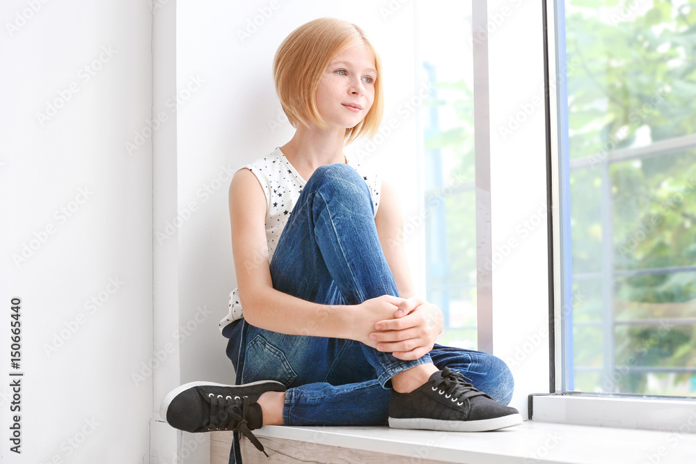 Cute teenager girl sitting near window