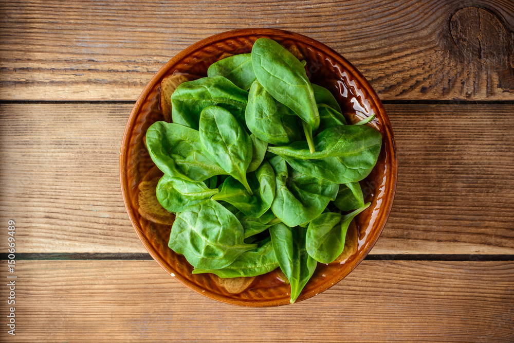 Fresh spinach leaves in bowl on rustic wooden table. Fresh spinach leaves in bowl on rustic wooden table.