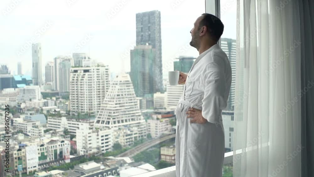 Young, happy man in bathrobe drinking coffee by window at home, super slow motion 120fps
Young, happy man in bathrobe drinking coffee by window at home, super slow motion 120fps