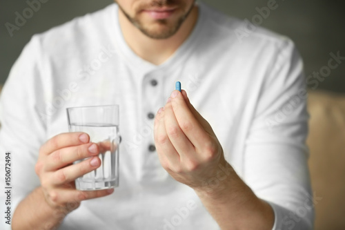 Young man with pill and glass of water, closeup