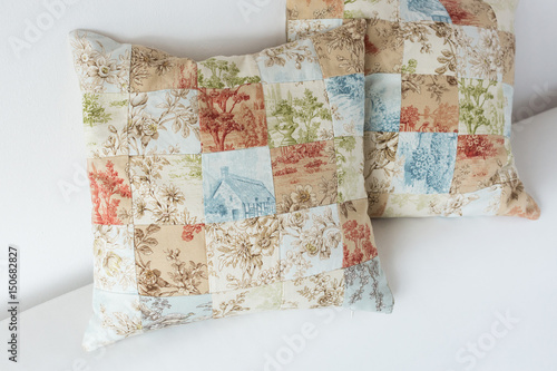 home cosiness, handcraft, sewing, patchwork concept - two decorative cushion made of patches in pastel shades with tender floral prints and image of country house
