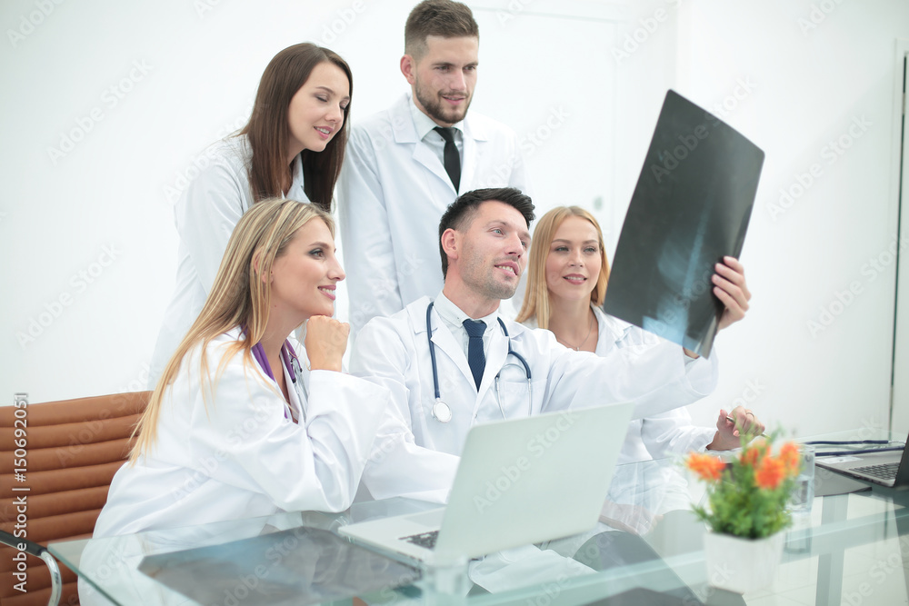 Smiling doctors are analyzind the x-ray. Medical office interior Smiling doctors are analyzind the x-ray. Medical office interior