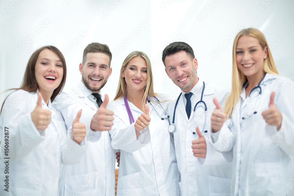 Smiling team of doctors at hospital making selfie and showing th Smiling team of doctors at hospital making selfie and showing th