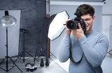Young professional photographer with camera in studio