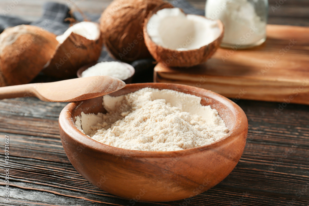 Coconut flour in bowl on dark wooden table Coconut flour in bowl on dark wooden table