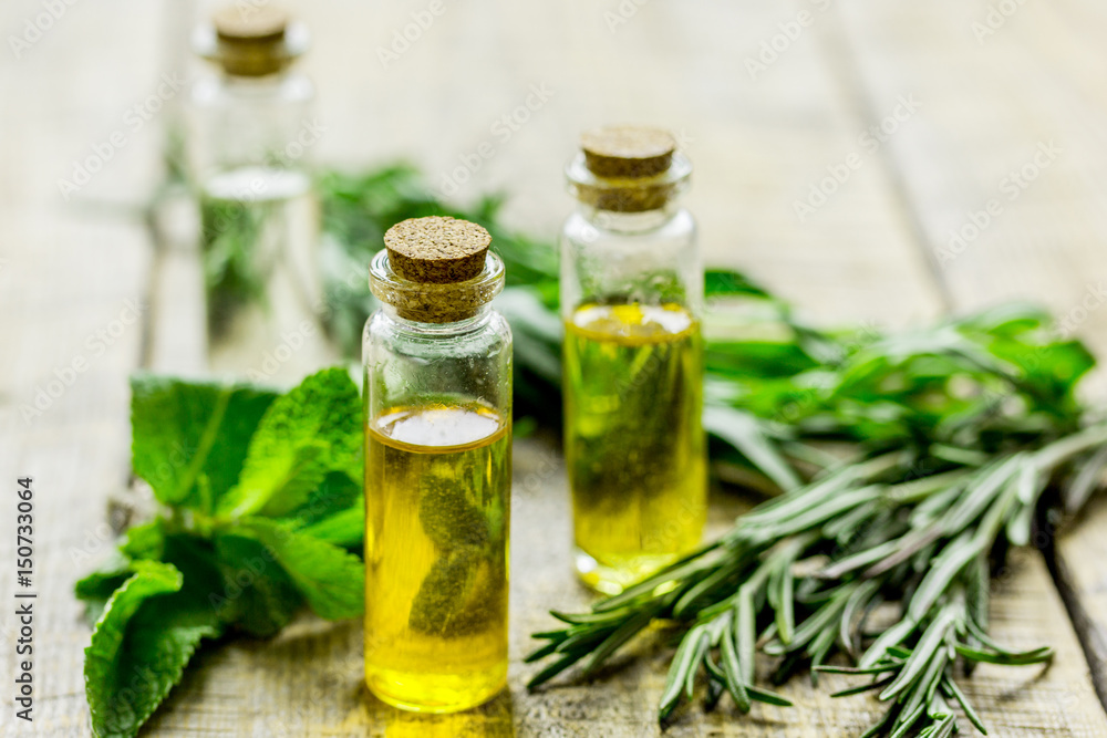 organic oil in bottle with rosemary and mint on light table background organic oil in bottle with rosemary and mint on light table background