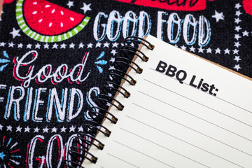 BBQ list concept on notebook and wooden board with picnic themed banner implying good friends and food