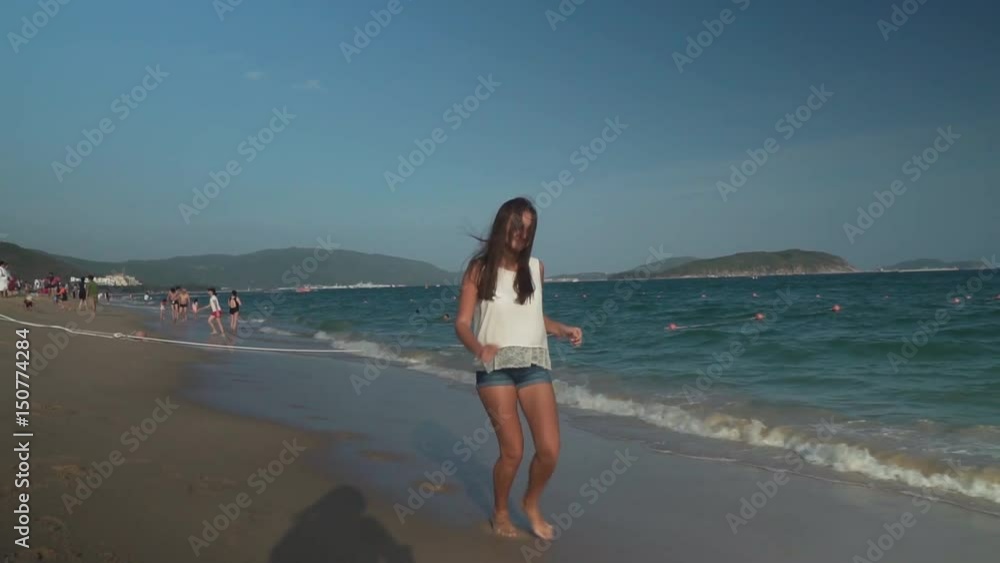 Happy young girl running along the beach of South China Sea, Yalong Bay slow motion stock footage video Happy young girl running along the beach of South China Sea, Yalong Bay slow motion stock footage video