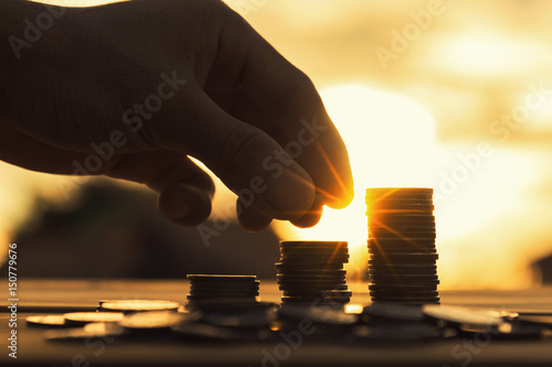 Saving money concept preset by Male hand putting money coin stack growing business.