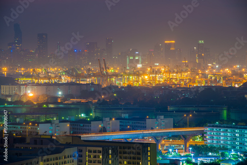 Container port with cityscape at night in Bangkok, Thailand.