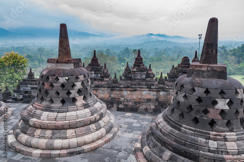 Borobudur buddhist temple with mountain and fog in the morning day in Yogyakarta, Java, Indonesia. (UNESCO World Heritage Site)